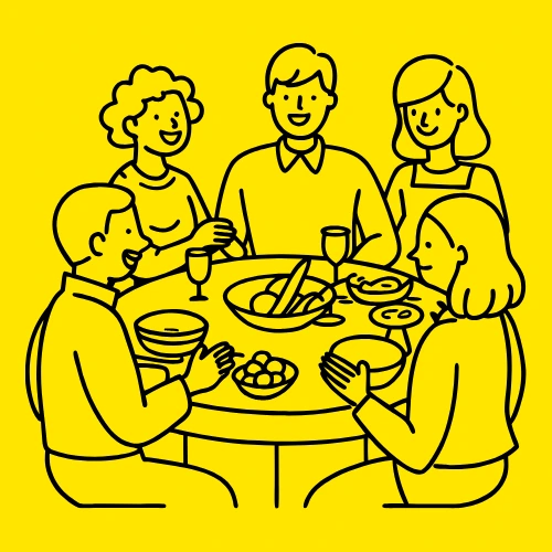 A group of people smiling around a dinner table.